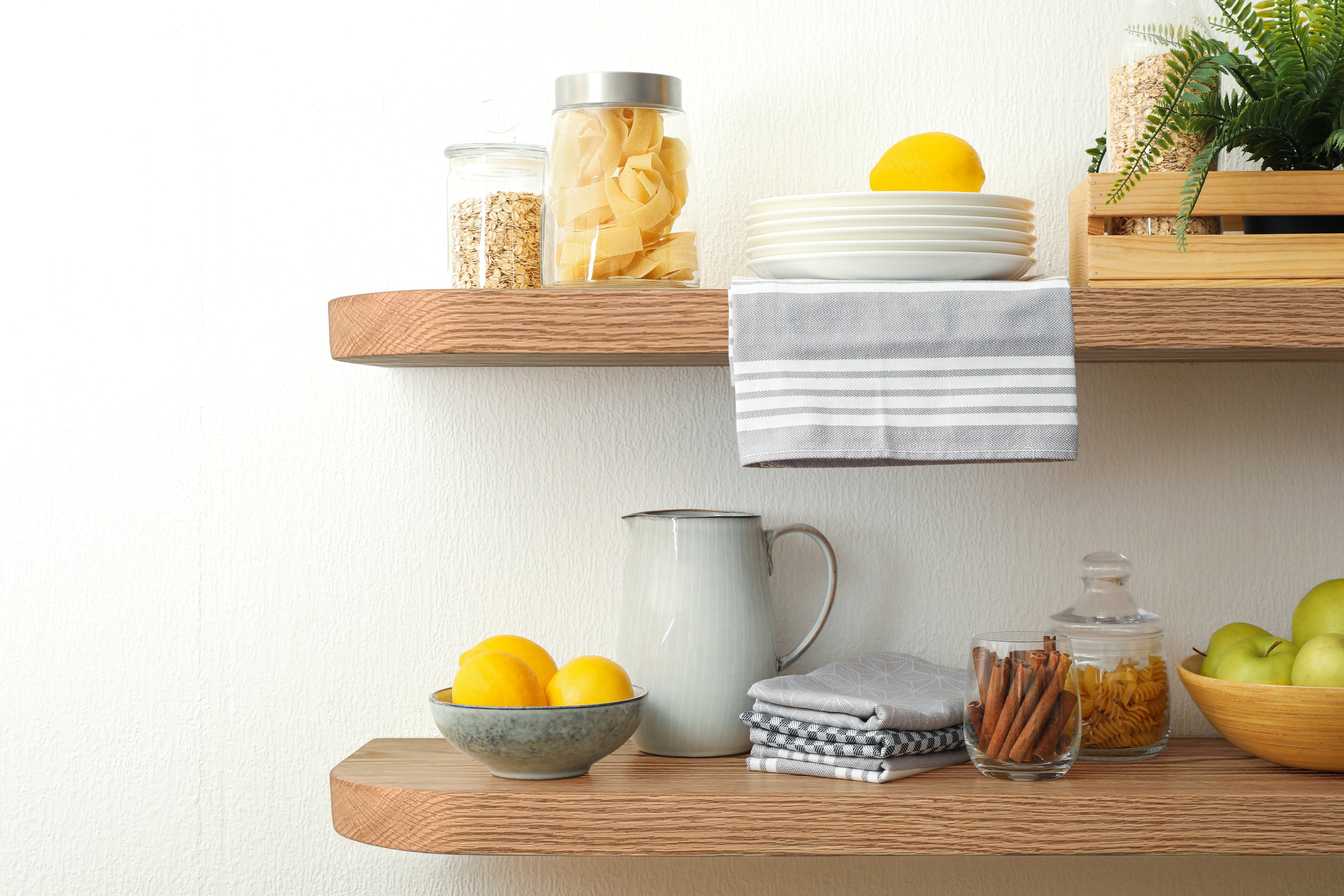 Two thick oak floating shelves with rounded corners are in a kitchen with foot items displayed.